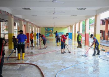 GURU dan kakitangan sekolah membersihkan kelas dan kawasan selepas dilanda banjir di Sekolah Kebangsaan Tengku Ampuan Intan, Kuala Berang, Terengganu, semalam. -UTUSAN/PUQTRA HAIRRY