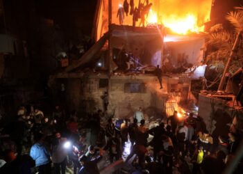 PENDUDUK Palestin mencari mangsa terperangkap bawah runtuhan bangunan menggunakan lampu dari telefon bimbit mereka di Rafah, selatan Semenanjung Gaza. - AFP