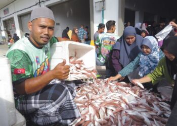 ZUHAIRI Hashim (kiri) menunjukkan ikan kerisi yang dijual pada harga RM10 bagi dua kilogram di premis kedai ikannya di Bandar Utama, Gua Musang, Kelantan.-UTUSAN/AIMUNI TUAN LAH