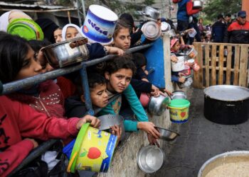 KANAK-KANAK Palestin beratur untuk mengambil makanan di pusat bantuan kem pelarian Rafah di selatan Gaza.-AFP