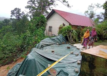 HAWA Daud (kiri) melihat hakisan tanah yang  di belakang rumahnya di Kampung Felda Belara, Kuala Nerus, Terengganu. - UTUSAN/TENGKU DANISH BAHRI TENGKU YUSOFF