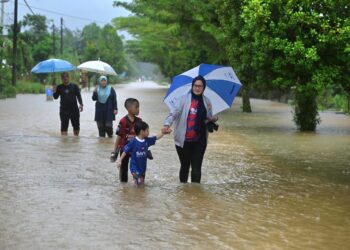 PENDUDUK meredah air untuk meninjau banjir di Pengkalan Ajal, Hulu Terengganu, semalam. - UTUSAN/PUQTRA HAIRRY ROSLI