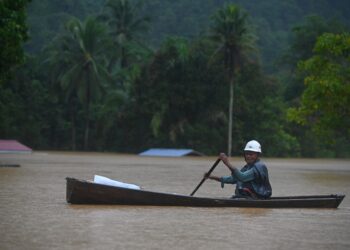 SEORANG penduduk menaiki perahu melihat keadaan banjir di Kampung Belimbing, Jongok Batu, Dungun, semalam. - UTUSAN/PUTRA HAIRRY ROSLI