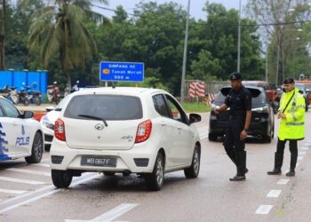 ANGGOTA polis mengawal lalulintas di selepas jalan Pasir Mas-Rantau Panjang, Kelantan ditutup akibat banjir-UTUSAN/KAMARUL BISMI KAMARUZAMAN.