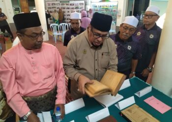 HARITH Fadzilah Abdul Halim (dua dari kiri) melihat buku yang dipamerkan dalam program penghargaan ulang tahun ke-90 penerbitan Kitab Bahrul Madzi, karya almarhum Syeikh Mohamad Idris Al-Marbawi di Padang Rengas, Perak hari ini. - UTUSAN