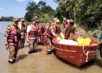 ZAINAL Madasin (tiga, kiri) semasa mengagihkan bantuan bersama Yayasan Raja Shamri di kepada penduduk di Kampung Teluk Jering, Tumpat, Kelantan. - UTUSAN/ROHANA ISMAIL