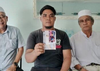 MOHAMAD Zulashraf (tengah) menunjukkan gambar arwah bapanya yang ditemukan dalam keadaan rangka dalam semak selepas dua minggu dilaporkan hilang di rumahnya di Bagan Serai semalam. - UTUSAN/WAT KAMAL ABAS