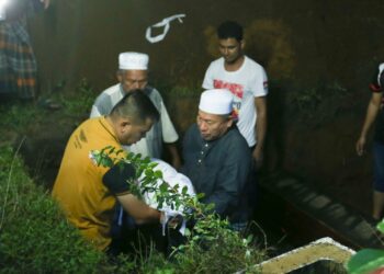 MOHD. Azman Mat Yaacob (kiri) mengiringi jenazah Muhammad Hariz Adrian untuk dikebumikan di Tanah Perkuburan Islam, Kampung Pintu Gerbang, Bachok, Kelantan petang tadi.-UTUSAN/ROHANA MOHD. NAWI