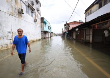 SEORANG  penduduk meredah banjir di kawasan Pekan Rantau Panjang, Kelantan hari ini-UTUSAN/KAMARUL BISMI KAMARUZAMAN.