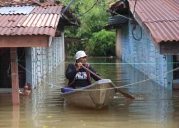 MUHAMMAD Zailani Che Awang mengayuh perahu selepas kawasan rumahnya di Rantau Panjang, Kelantan ditenggelami banjir hari ini-UTUSAN/KAMARUL BISMI KAMARUZAMAN.