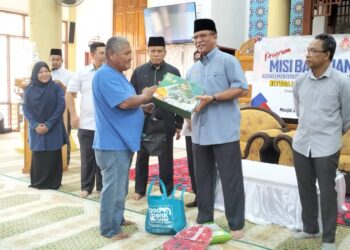 RUSLAN Said (dua kanan) menyampaikan sumbangan kepada salah seorang penerima di Masjid Jubli Perak Sultan Ismail Petra, Rantau Panjang, Kelantan.UTUSAN/ROHANA ISMAIL