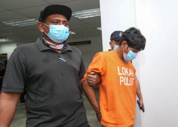 TERTUDUH (kanan) dibawa oleh anggota polis untuk perbicaraan di Mahkamah Sesyen Kota Bharu, Kelantan hari ini-UTUSAN/KAMARUL BISMI KAMARUZAMAN