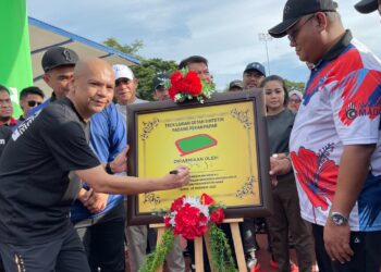 ARMIZAN Mohd. Ali (kiri) menandatangani plak perasmian trek larian getah sintetik di Padang Pekan Papar, Sabah, semalam.