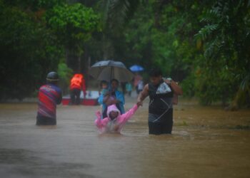 PENDUDUK meredah banjir untuk berpindah di Kampung Belimbing, Jongok Batu, Dungun, semalam. - UTUSAN/PUQTRA HAIRRY ROSLI