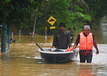 BEBERAPA penduduk meredah banjir di bandar Kuala Berang, Hulu Terengganu. - UTUSAN/PUQTRA HAIRRY ROSLI