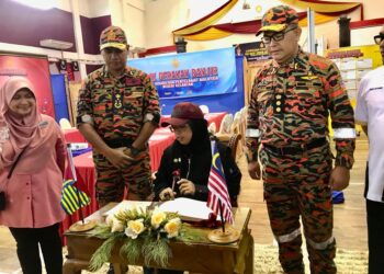 AIMAN Athirah Sabu (duduk) menandatangani buku lawatan di Ibu Pejabat Balai Bomba dan Penyelamat Kelantan di Tunjung Kota Bharu, Kelantan hari ini.- UTUSAN/ ROSLIZA MOHAMED
