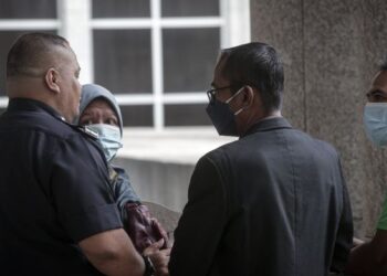 PEMBANTU operasi kolej vokasional (berbaju hitam dan memakai pelitup muka) hadir Mahkamah Sesyen Putrajaya bagi sebutan kes amang seksual yang dihadapinya. - UTUSAN/FAIZ ALIF AHMAD ZUBIR