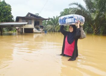 SEORANG penduduk meredah banjir di Kampung Pengkalan Ajal, Kuala Berang, Terengganu, semalam. - UTUSAPUQTRA HAIRRY ROSLI