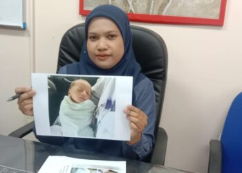 NOR Amelia Ali menunjukkan gambar bayi yang ditinggalkan di belakang rumah kedai minggu lalu dalam sidang akhbar di pejabat JKM Manjung di Lumut. - UTUSAN/SHAMSUL KAMAL AMARUDIN