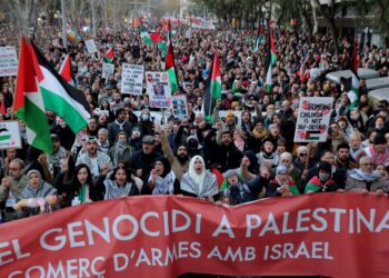 PENUNJUK perasaan memegang sepanduk dan mengibarkan bendera Palestin semasa perhimpunan menyokong rakyat  Gaza di Barcelona, kelmarin.-AFP