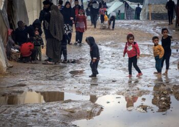 KANAK-kanak Palestin menyeberangi lopak air di kem sementara yang menempatkan penduduk kehilangan tempat tinggal, di Rafah di selatan Semenanjung Gaza.-AFP