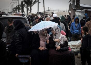 ​WANITA Palestin berbual-bual di bawah payung di kem sementara yang menempatkan penduduk Palestin yang kehilangan tempat tinggal, di Rafah di selatan Semenanjung Gaza.-AFP