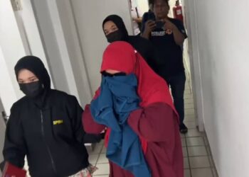 ROSLILAWATI Mukhtar (kanan) yang mengaku salah memalsukan permohonan bantuan persekolahan dibawa keluar dari Mahkamah Sesyen Kuala Terengganu, semalam. - UTUSAN/TENGKU DANISH BAHRI TENGKU YUSOFF