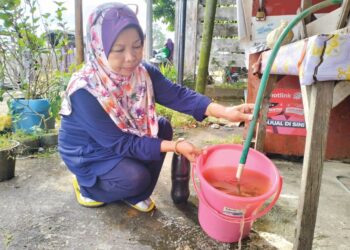 SEORANG penduduk Kelantan menunjukkan air keruh yang keluar dari paip di rumahnya.- UTUSAN/ROHANA ISMAIL.