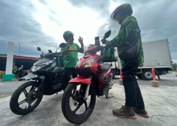 HASMAWIE Abdullah (kiri) dan Khairul Rijal Osman semasa menunggu pesanan dari sebuah kedai makan untuk dihantar kepada pelanggan di Kangar, Perlis. - UTUSAN/MOHD. HAFIZ ABD. MUTALIB