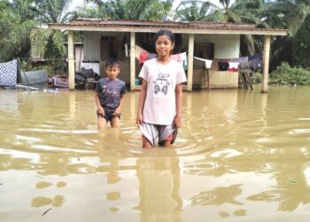 DUA kanak-kanak berada di pekarangan rumah Mek Yam Ahmad di Kampung Bendang Perol To' Deh, Rantau Panjang, Kelantan yang dinaiki air, semalam. UTUSAN/ROHANA ISMAIL