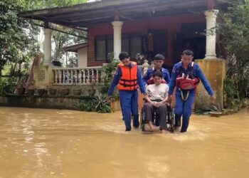 ANGGOTA APM membantu menyelamatkan salah seorang anak Kamaludin yang OKU selepas rumah mereka dinaiki air di Kampung Keliyu, Serdang, Dungun, semalam. - UTUSAN/NIK NUR IZZATUL HAZWANI NIK ADNAN