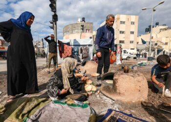 SEORANG wanita membakar roti di luar di kem sementara penduduk Palestin di Rafah di selatan Semenanjung Gaza.-AFP