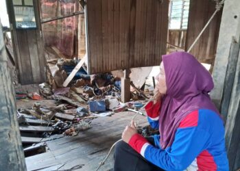 JALINA Abdullah melihat keadaan lantai di ruang tamu dan biliknya yang runtuh akibat banjir di Kampung Shukor, Hulu Dungun, Dungun, semalam. - UTUSAN/NIK NUR IZZATUL HAZWANI NIK ADNAN