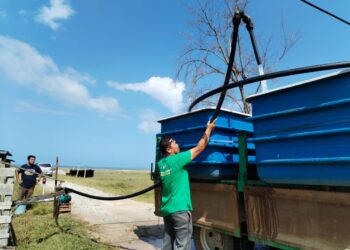 FADZIL Zabidee Zakaria mengisi air daripada telaga tiup ke dalam tangki untuk diagihkan kepada penduduk di Kampung Air Tawar, Besut, hari ini. - UTUSAN/WAN ZURATIKAH IFFAH WAN ZULKIFLI