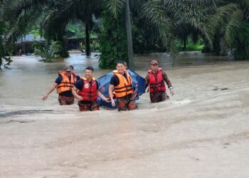 ANGGOTA bomba membawa keluarga mangsa banjir di Ladang Mados, Sungai Tiram.