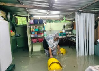 EMYLIANA Mohd  Din menarik tong gas yang 'hanyut dalam rumahnya di Lorong Dua Kampung Baru, Kluang.