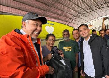 AHMAD ZAHID Hamidi (kiri) menyampaikan sumbangan kepada mangsa banjir sambil diperhatikan oleh Onn Hafiz Ghazi ketika melawat PPS SK Taman Kota Jaya, Kota Tinggi.