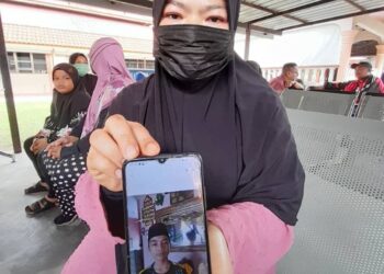 SUHANA Salman menunjukkan gambar Muhammad Airell yang lemas bersama rakannya ketika mandi di parit di Kampung Perpat, Tanjung Sedili, Kota Tinggi.