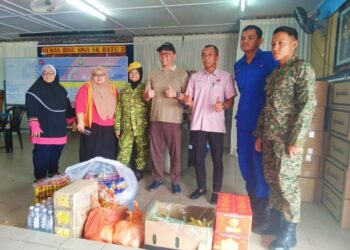 MD. NORHALIM Md. Amin (empat dari kiri) menyerahkan makanan dan minuman kepada mangsa banjir yang ditempatkan di PPS Sekolah Kebangsaan Batu Tiga, Kluang.