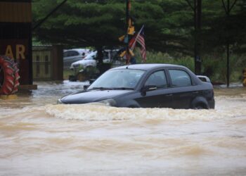 SEBUAH kereta meredah banjir selepas jalan Pasir Puteh ke Kota Bharu dekat Kampung Bukit Abal, Pasir Puteh, Kelantan hari ini yang ditenggelami banjir sedalam 0.5 meter.-UTUSAN/KAMARUL BISMI KAMARUZAMAN.