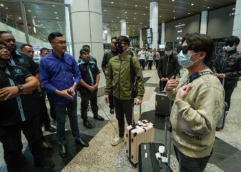 HISHAMMUDIN Hashim (kiri) berbual dengan mangsa sindiket pemerdagangan manusia selepas tiba di KLIA, Terminal 1, Sepang. - UTUSAN/FAISOL MUSTAFA