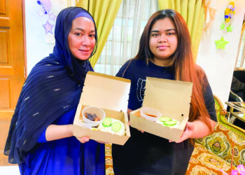 ROSFARIDA Shamsudin (kiri) bersama Nik Nordamia (kanan) mula menjual nasi lemak dari rumah mereka di Air Putih, Kuantan, Pahang. - UTUSAN/NORHAFIZAN ZULKIFLI