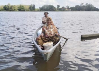 RAHIMAH Che Mat terpaksa menggunakan perahu untuk urusan harian berikutan banjir termenung di Kampung Kubang Sawa, Pengkalan Kubor, masih belum surut. - UTUSAN/ROHANA ISMAIL