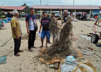 Rosli Ahmad (dua dari kiri) melihat Mohd. Muszairi Mohamed (tiga dari kanan) menunjukkan jaring pukat hanyut yang koyak rabak dipenuhi rumput dan sampah di Pantai, Puteri, Melaka. UTUSAN/AMRAN MULUP