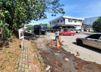 AHMAD Jusoh (kanan) dan Fauzan Abdul Aziz menunjukkan keadaan jalan yang berlopak serta kon yang diletakkan di Jalan Tunku Bendahara, Kulim. - UTUSAN/AZAHAR HASHIM