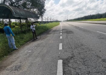 PENDUDUK menunjukkan keadaan Jalan Persekutuan Hutan Melintang ke Sabak Bernam yang lengang berikutan pengguna memilih WCE. - UTUSAN/AIN SAFRE BIDIN