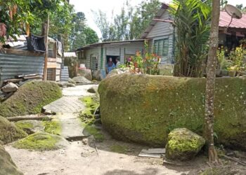 RUMAH penduduk di Kampung Batu Berangkai dikelilingi bongkah batu besar yang dibina berhampiran sungai di Kampar. - UTUSAN/MEGAT LUTFI MEGAT RAHIM