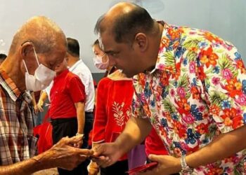 R. RAMANAN menyampaikan sumbangan kepada seorang warga emas pada program sambutan Tahun Baharu Cina di Subang, hari ini.