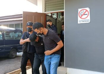 ANGGOTA polis berpangkat sarjan (tengah) dibawa ke Mahkamah Majistret Parit untuk permohonan sambung reman hari ini. - UTUSAN