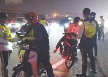 ANGGOTA polis trafik membuat pemeriksaan terhadap beberapa penunggang motosikal di Lebuhraya Persekutuan, berdekatan Seskyen 7, Shah Alam, Selangor, awal pagi semalam. - UTUSAN/ MOHAMAD NAUFAL MOHAMAD IDRIS